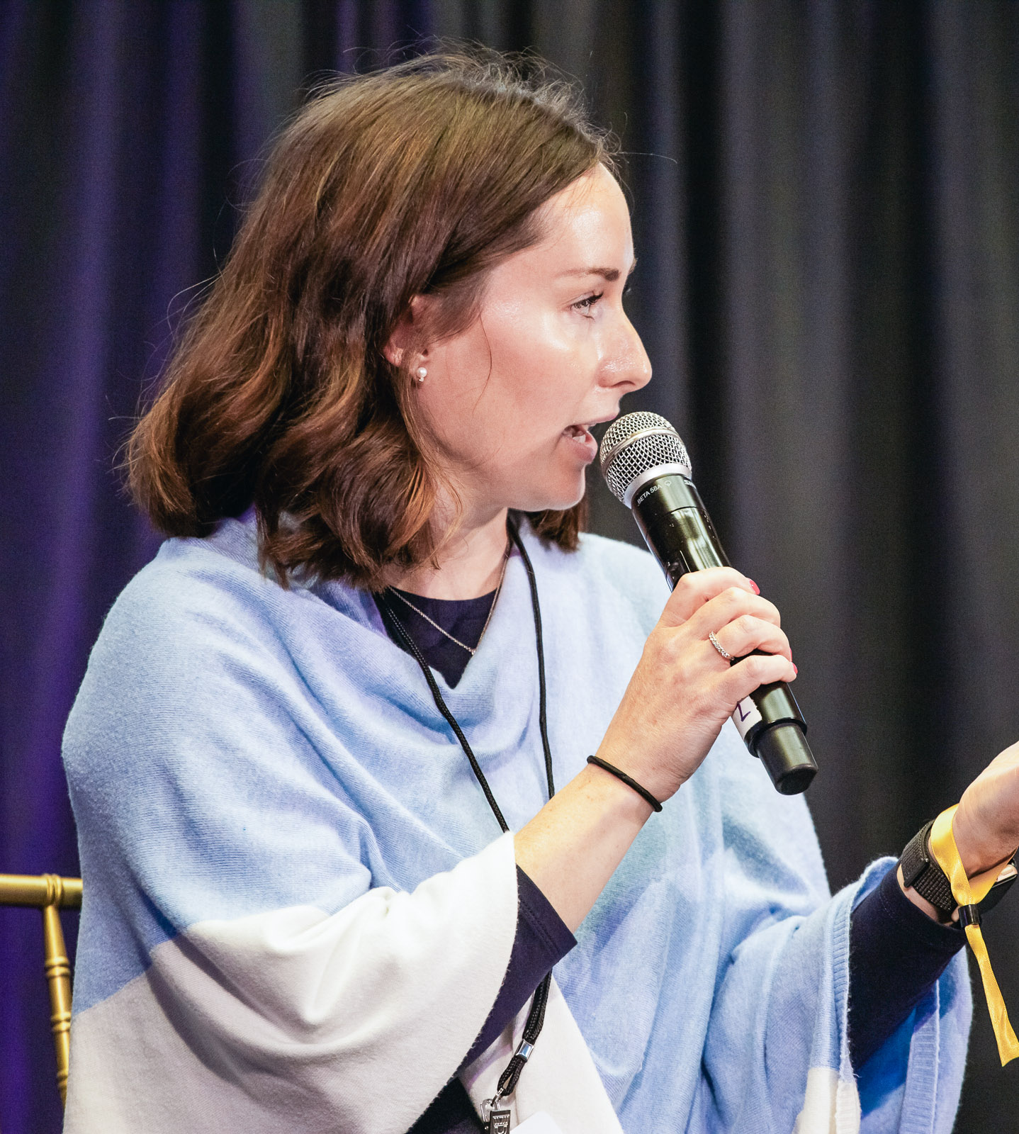 Olivia Svrchek speaking on a panel, holding a microphone