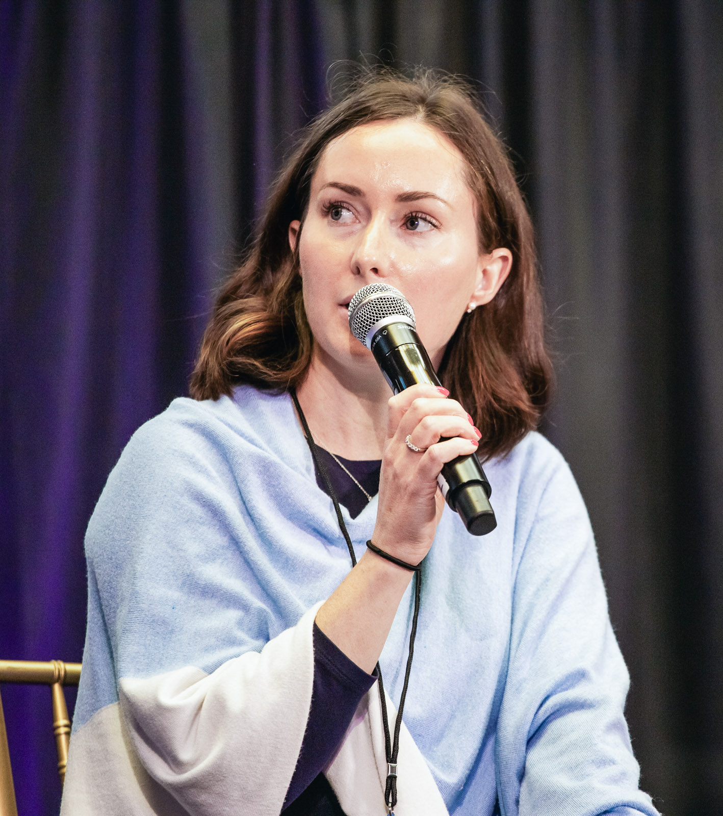 Olivia Svrchek speaking on a panel, holding a microphone